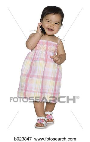 Stock Photo - baby girl in a pink dress holding a cell phone. Fotosearch