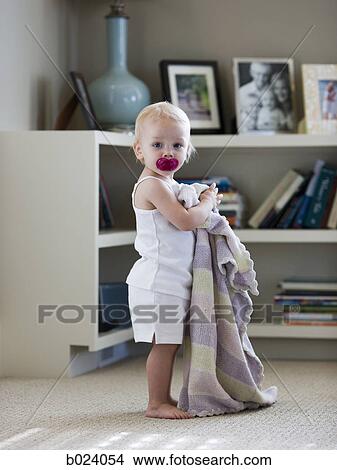 Picture - baby standing with blanket and pacifier. Fotosearch