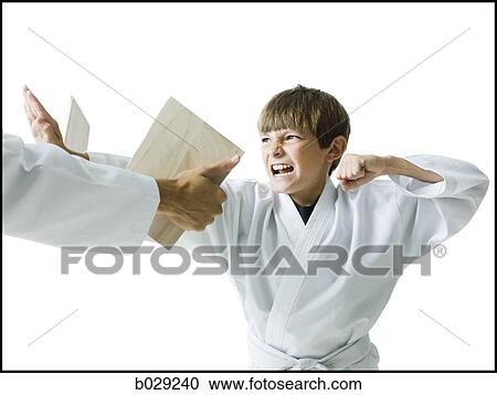 Stock Image - boy breaking a board using karate. Fotosearch