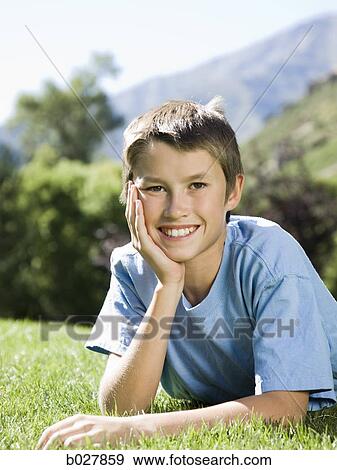 boy lying on the grass in the park View Large Photo Image Stock Photo - boy lying on the grass in the park. Fotosearch