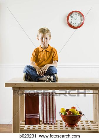 boy sitting on a kitchen table View Large Photo Image Stock Image - boy sitting on a kitchen table. Fotosearch