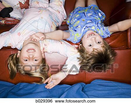 Stock Photograph - brother and sister lying upside down on the couch. Fotosearch