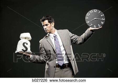 businessman holding a clock and a bag of money View Large Photo Image Stock Photograph - businessman holding a clock and a bag of money. Fotosearch