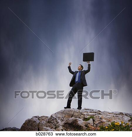 businessman holding his arms in the air on the top of a cliff View Large Photo Image Stock Image - businessman holding his arms in the air on the top of a cliff. Fotosearch