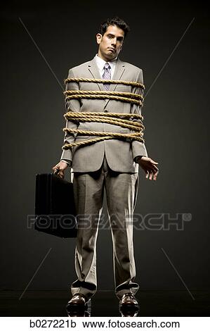 Stock Image - businessman in a full suit tied up with a rope around his mid section. Fotosearch