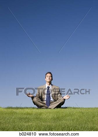 Stock Image - businessman meditating on the grass. Fotosearch