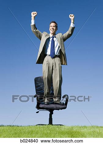 Stock Image - businessman standing on his chair outside. Fotosearch