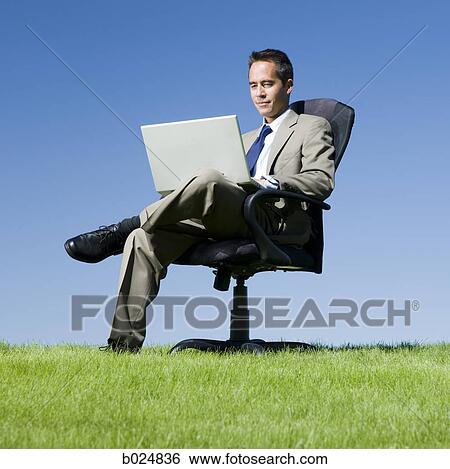 businessman using his laptop in a grassy field View Large Photo Image Stock Photograph - businessman using his laptop in a grassy field. Fotosearch