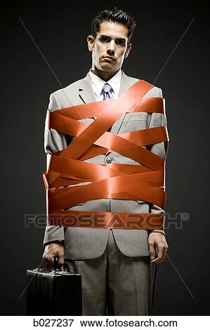 Stock Photo - businessman wrapped up with red tape. Fotosearch