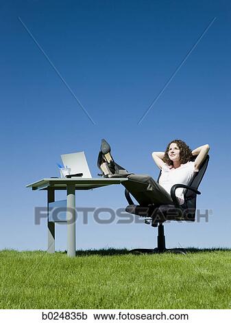 Stock Image - businesswoman at her desk in a grassy field. Fotosearch