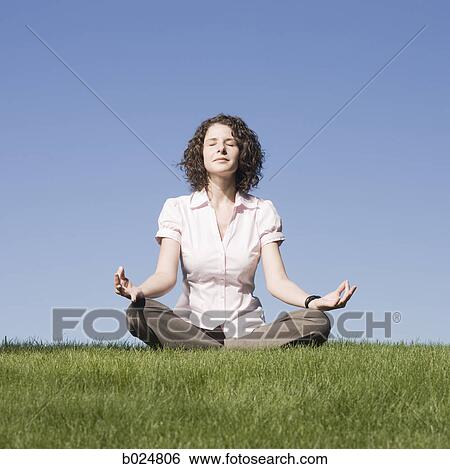Stock Photograph - businesswoman meditating on the grass. Fotosearch