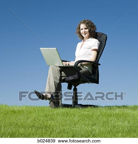 Stock Photo - businesswoman using her laptop in a busy field. Fotosearch