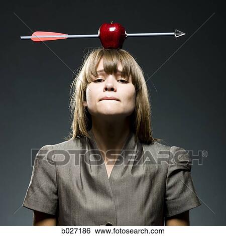 Stock Photograph - businesswoman with an apple with an arrow through it on her head. Fotosearch