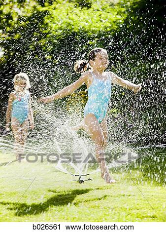Stock Image - children playing in a sprinkler. Fotosearch