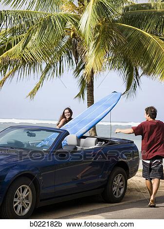 Stock Image - couple going to the beach to surf. Fotosearch