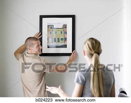 Stock Image - couple hanging a picture. Fotosearch