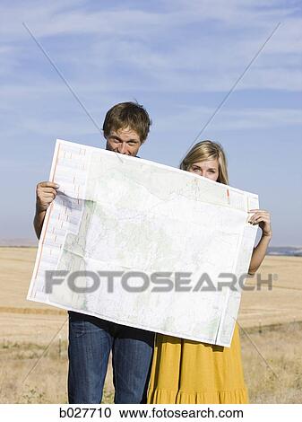 Stock Image - couple looking at a map on the side of the road. Fotosearch
