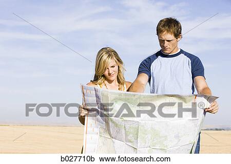 Stock Image - couple looking at a map on the side of the road. Fotosearch