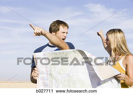 Stock Image - couple looking at a map on the side of the road. Fotosearch