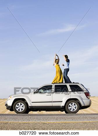 couple on the roof of their car on the side of the road View Large Photo Image Stock Image - couple on the roof of their car on the side of the road. Fotosearch