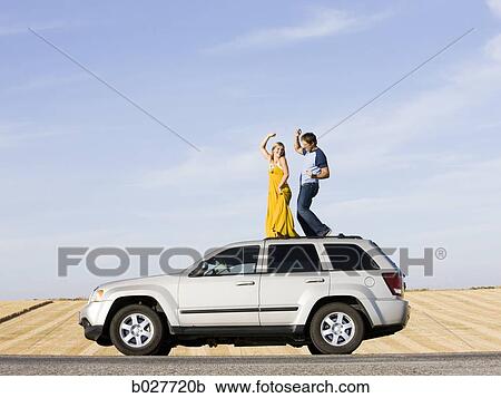 couple on the roof of their car on the side of the road View Large Photo Image Stock Image - couple on the roof of their car on the side of the road. Fotosearch