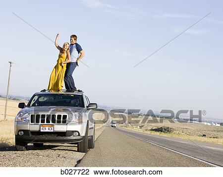 couple on the roof of their car on the side of the road View Large Photo Image Stock Image - couple on the roof of their car on the side of the road. Fotosearch