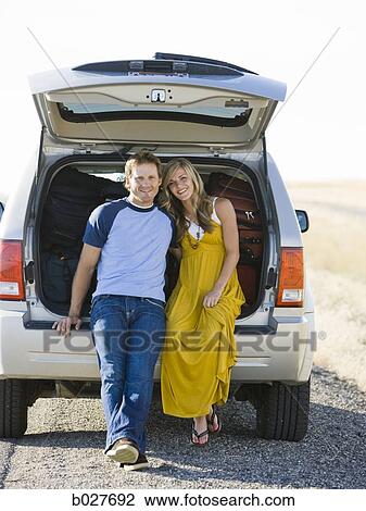 Stock Image - couple sitting in the back of their car on a road trip. Fotosearch