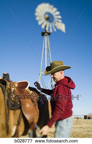 cowboy saddling up his horse View Large Photo Image Stock Photo - cowboy saddling up his horse. Fotosearch
