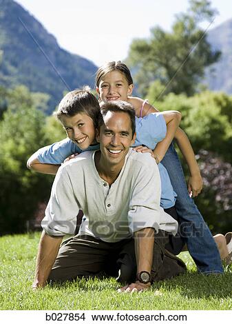 Picture - dad in the park with his two kids. Fotosearch