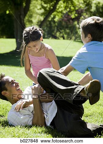 Stock Photo - dad in the park with his two kids. Fotosearch