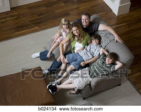 Picture - family sitting on sofa in living room. Fotosearch