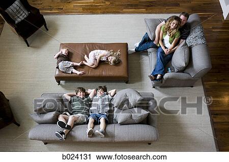 Stock Image - family sitting on sofa in living room. Fotosearch