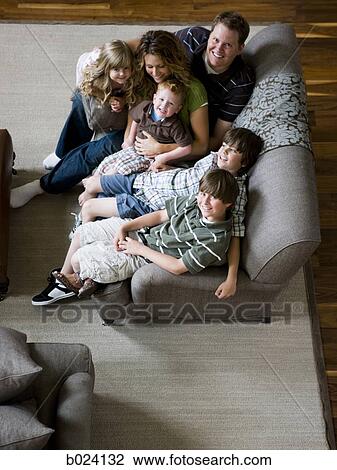 family sitting on sofa in living room View Large Photo Image Stock Image - family sitting on sofa in living room. Fotosearch