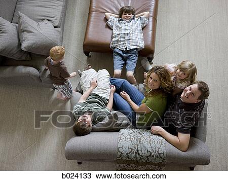 Stock Image - family sitting on sofa in living room. Fotosearch