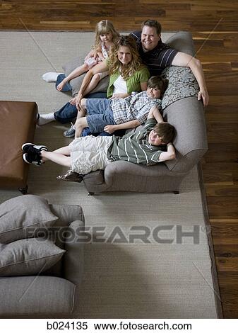 family sitting on sofa in living room View Large Photo Image Stock Photography - family sitting on sofa in living room. Fotosearch