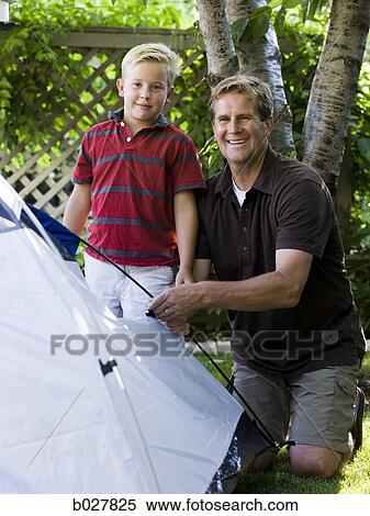 Stock Photography - father and son putting up a tent in the backyard. Fotosearch