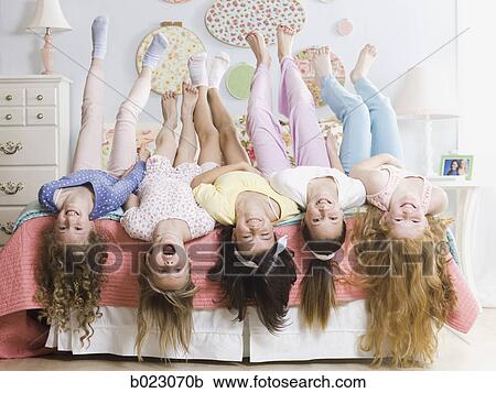 Stock Image - five girls on a bed upside down. Fotosearch