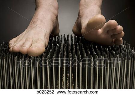 Stock Image - foot walking on nails. Fotosearch