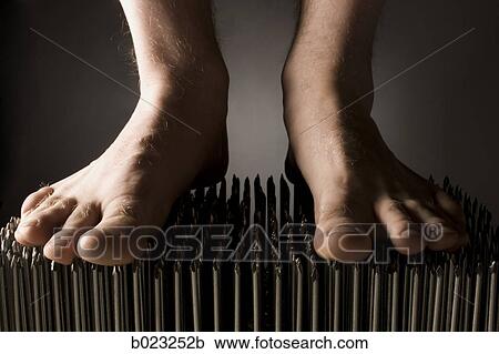 Stock Image - foot walking on nails. Fotosearch