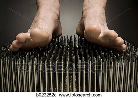 Stock Image - foot walking on nails. Fotosearch