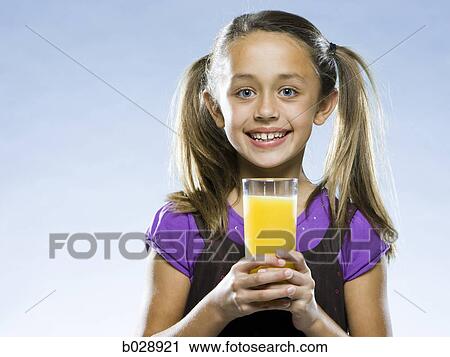 girl holding a glass of orange juice and looking at the camera View Large Photo Image Stock Image - girl holding a glass of orange juice and looking at the camera. Fotosearch