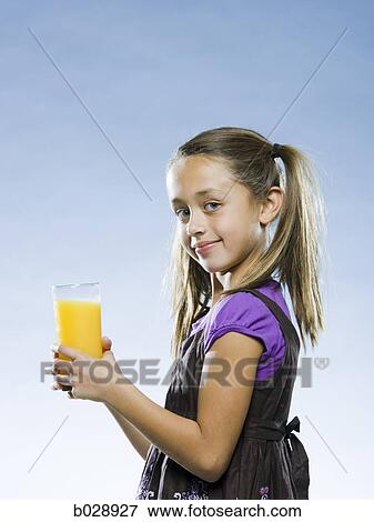 girl holding a glass of orange juice and looking at the camera View Large Photo Image Stock Photo - girl holding a glass of orange juice and looking at the camera. Fotosearch