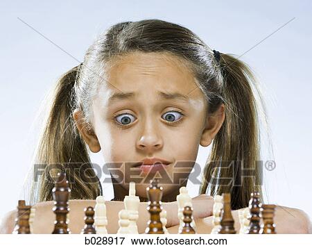 Stock Photo - girl looking at a chess set with disbelief. Fotosearch