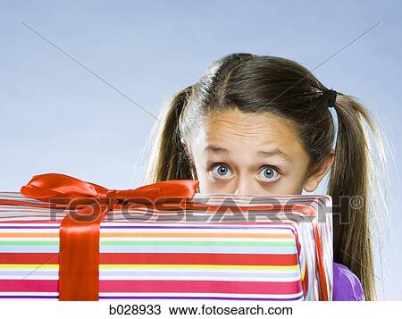 girl looking at the camera from behind a present View Large Photo Image Stock Image - girl looking at the camera from behind a present. Fotosearch