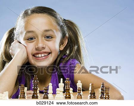 girl looking at the camera while sitting at a game of chess View Large Photo Image Picture - girl looking at the camera while sitting at a game of chess. Fotosearch