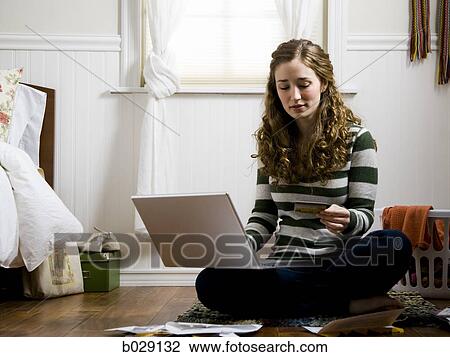 Stock Image - girl making an online purchase on a laptop with a credit card. Fotosearch