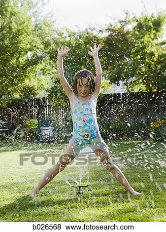 Stock Photo - girl playing in a sprinkler. Fotosearch