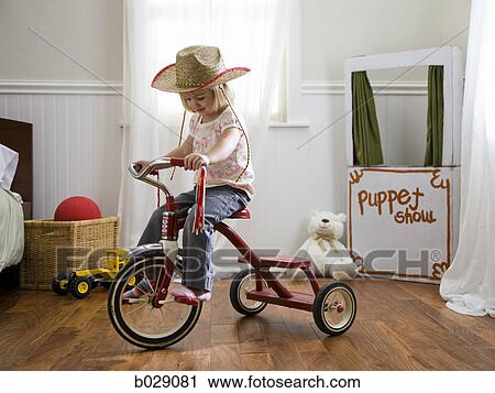 girl riding a tricycle wearing a cowboy hat View Large Photo Image Stock Image - girl riding a tricycle wearing a cowboy hat. Fotosearch