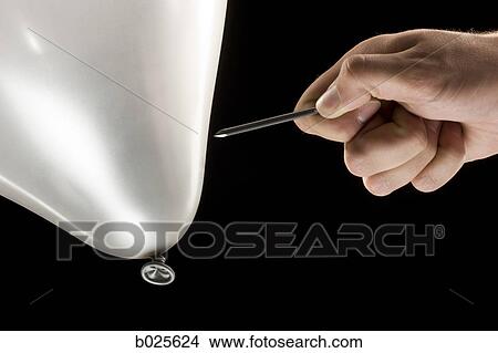 Picture - hand about to pop a balloon with a nail. Fotosearch