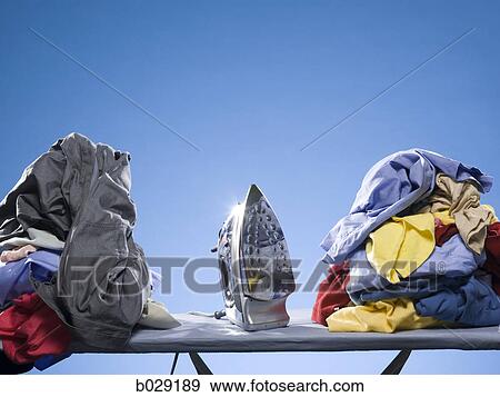 Stock Photo - iron next to a pile of clothes. Fotosearch